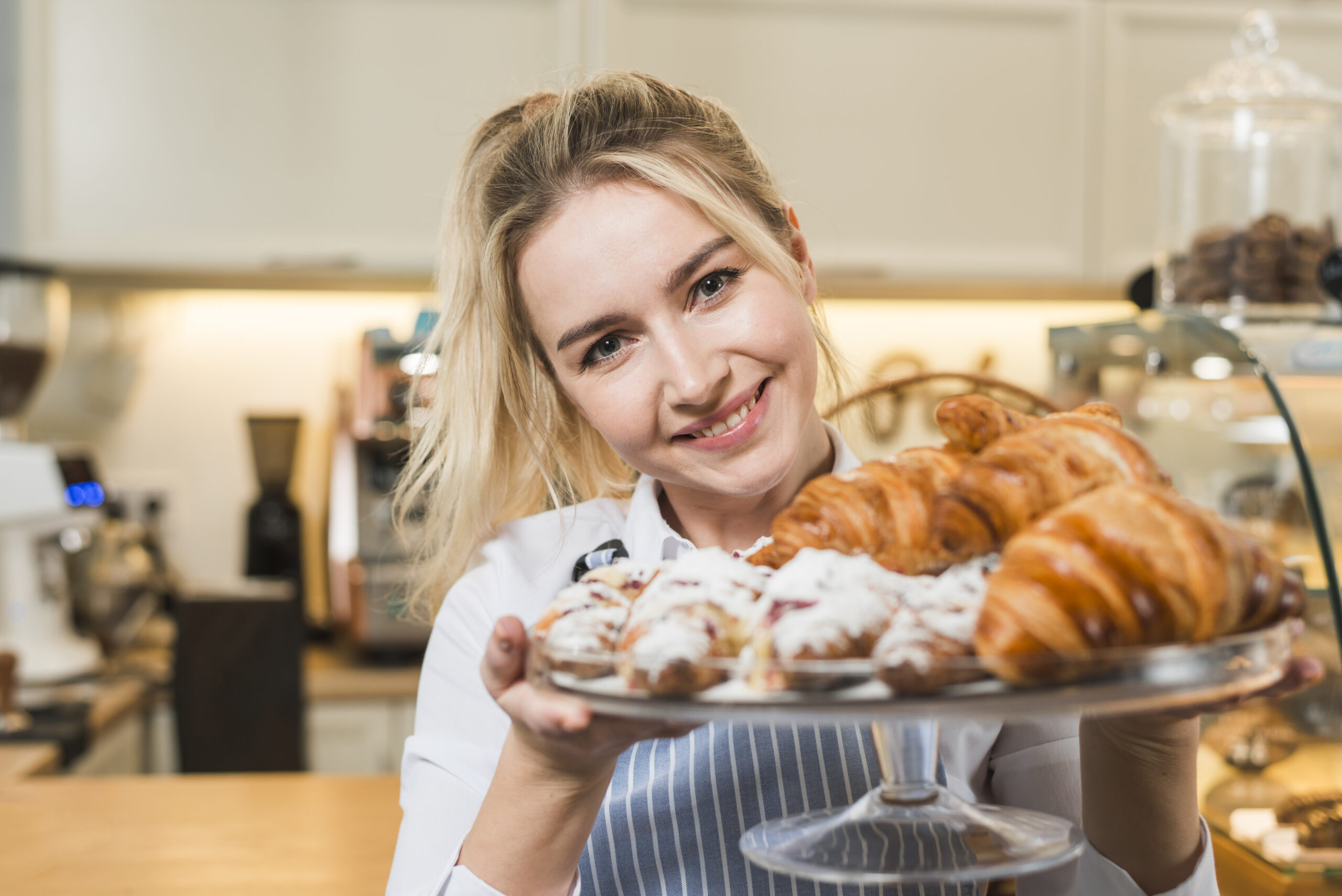 portrait-smiling-young-woman-holding-baked-croissant-cake-stand